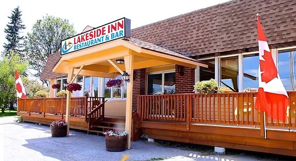 A Lakeside Inn restaurant and bar with a wooden exterior, a covered patio, and red and white flags.