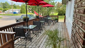 Une terrasse extérieure avec des tables et des chaises en bois, des parasols rouges et des plantes en pot.