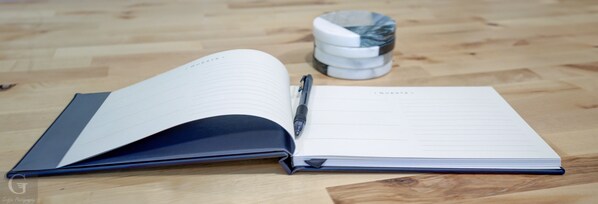 An open notebook with lined pages and a pen on a wooden surface.