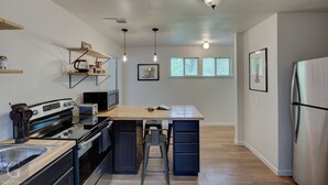 Una cocina moderna con una isla central, electrodomésticos integrados e iluminación colgante.