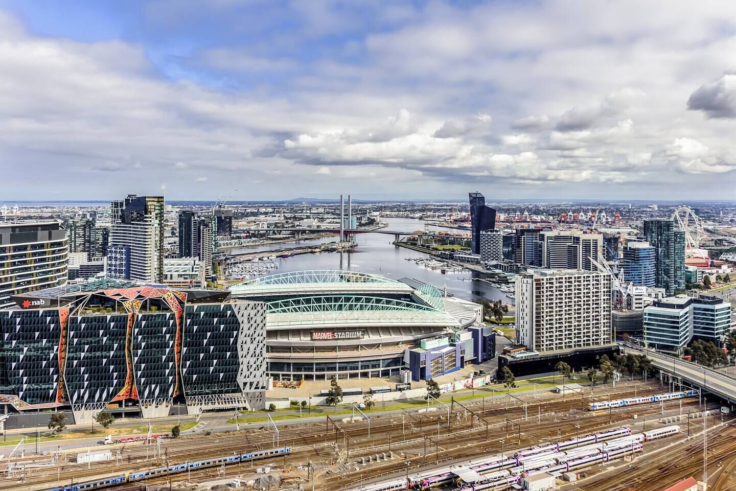 A cityscape with a stadium, modern buildings, and a river.