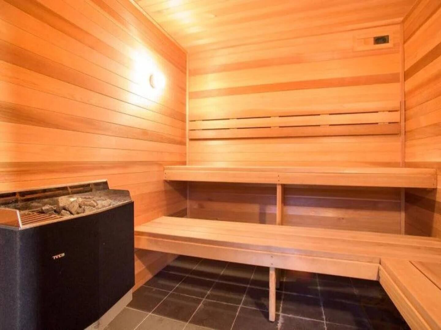 A sauna with wooden walls and benches, a tiled floor, and a visible heater.