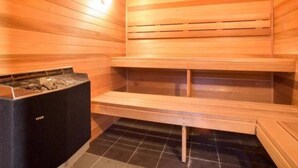 A sauna with wooden walls and benches, a tiled floor, and a visible heater.