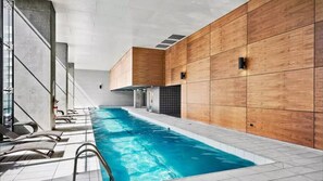 Une piscine intérieure au design moderne, avec des murs recouverts de panneaux en bois et un sol carrelé.