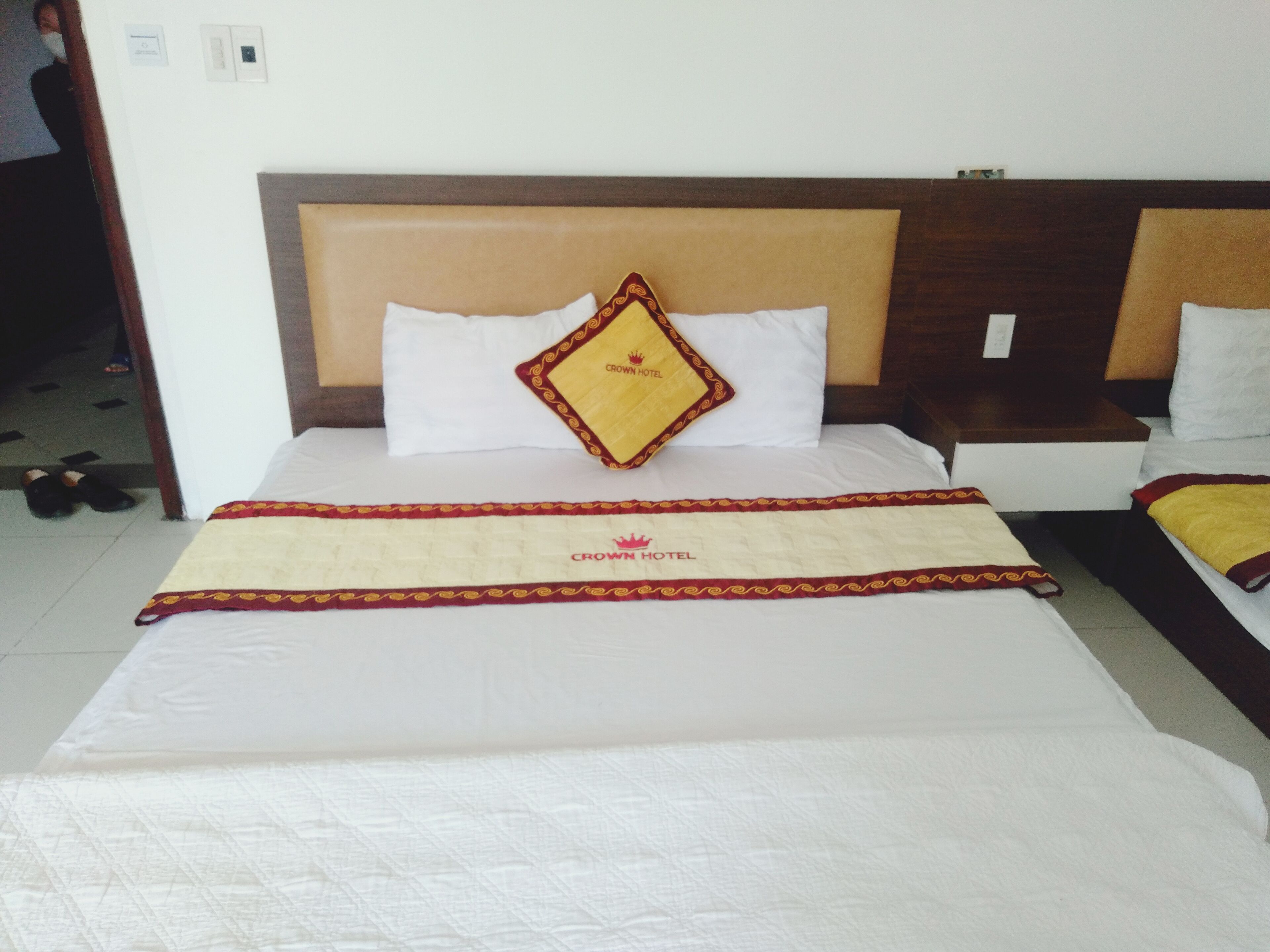 A hotel room with a large bed, a headboard, and a bedside table.