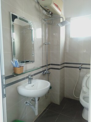 A bathroom with a white sink, a mirror, a shower, and a toilet. - Khach san Crown (Phan Dinh Phung)