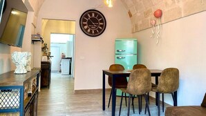 A dining area with a vintage clock, a teal refrigerator, and a wooden dining table with chairs. - The Pink Pumo (Monopoli)