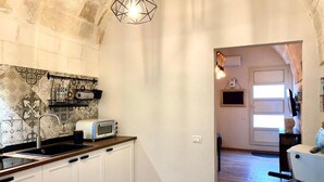 A kitchen with white cabinets, a toaster, and a hanging light fixture. - The Pink Pumo (Monopoli)