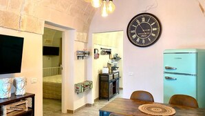 A dining area with a wooden table, chairs, and a vintage clock on the wall. - The Pink Pumo (Monopoli)