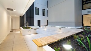 A modern outdoor area with a wooden deck, planters, and a minimalist design.