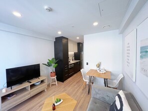 A modern living room with a flat-screen TV, a dining table, and a sofa.