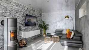 A modern living room with a fireplace, a sofa, a TV, and a plant. - Modern Oasis w/ HotTub, View, Gym (Oberbettingen)