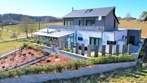 A modern two-story house with a flat roof, large windows, and a covered patio area. - Modern Oasis w/ HotTub, View, Gym (Oberbettingen)