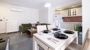 A modern living room with a sofa, coffee table, and dining table set for four. There is a kitchen area with a refrigerator and a tiled backsplash. - The Canka Hotel Residance Istanbul (Istanbul)