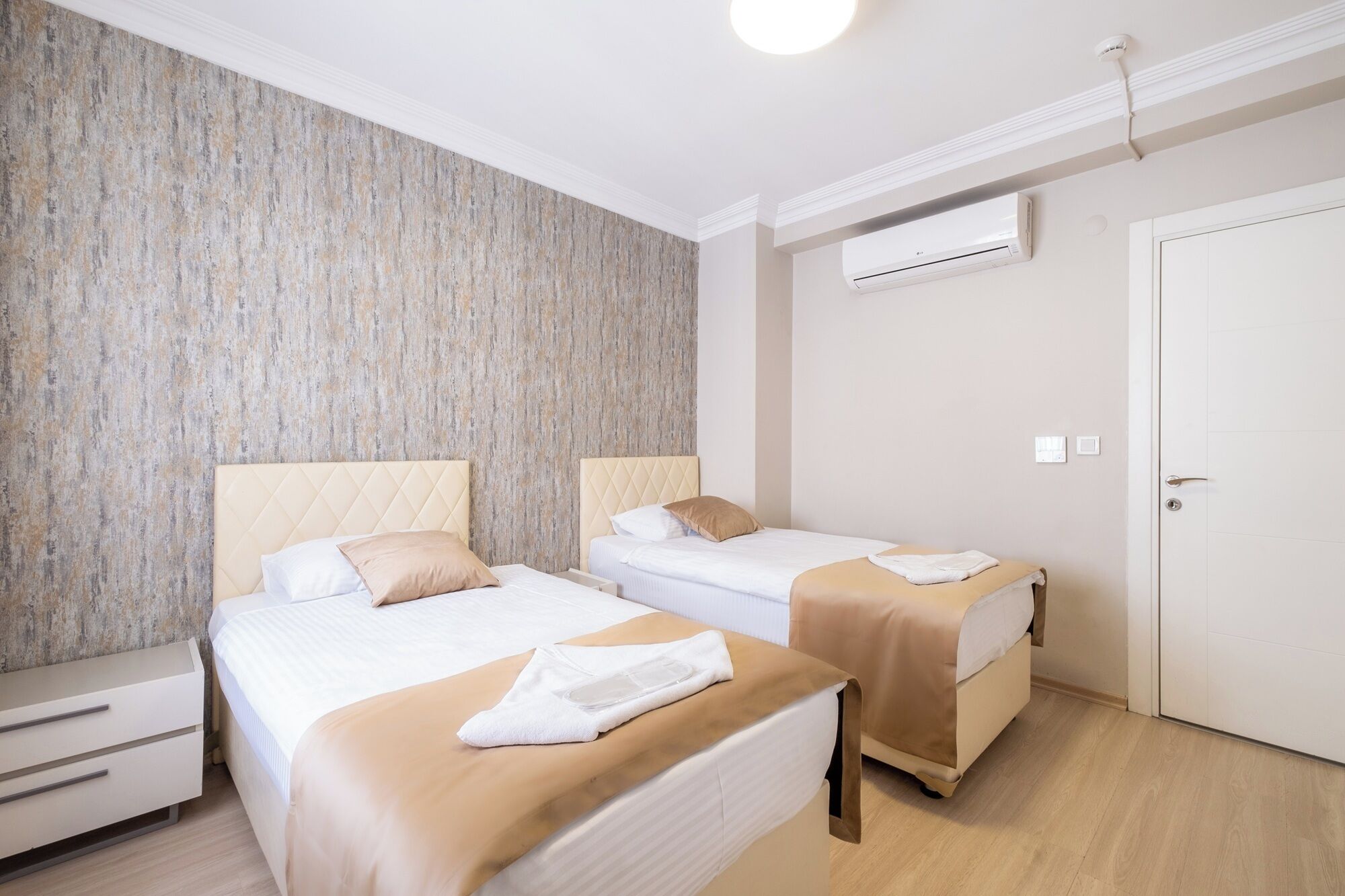 Une chambre d’hôtel avec deux lits, une armoire, un appareil de climatisation et une porte.