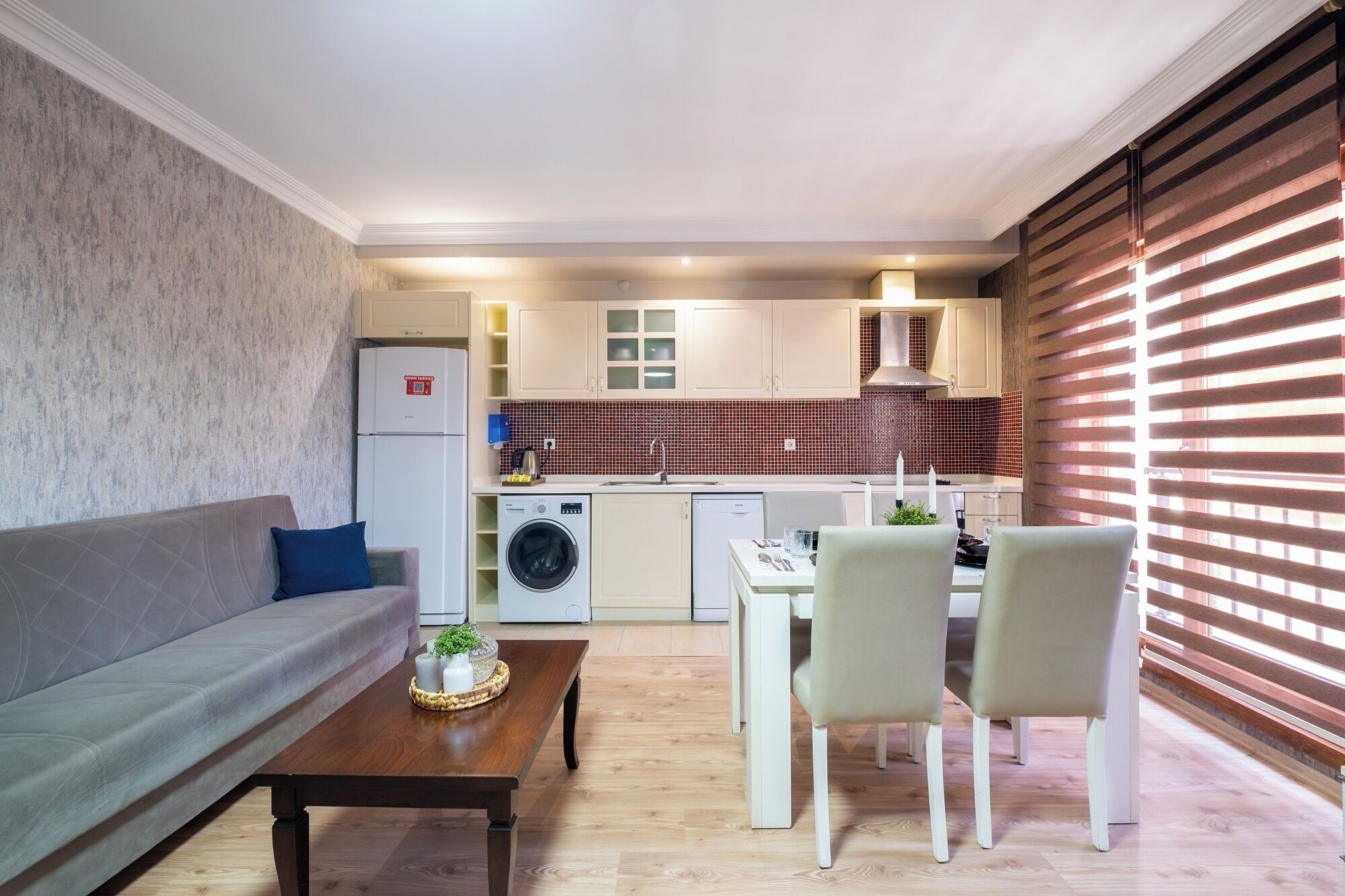 Un espace de vie compact comprenant un canapé, une table à manger, des chaises, un lave-linge et une kitchenette.