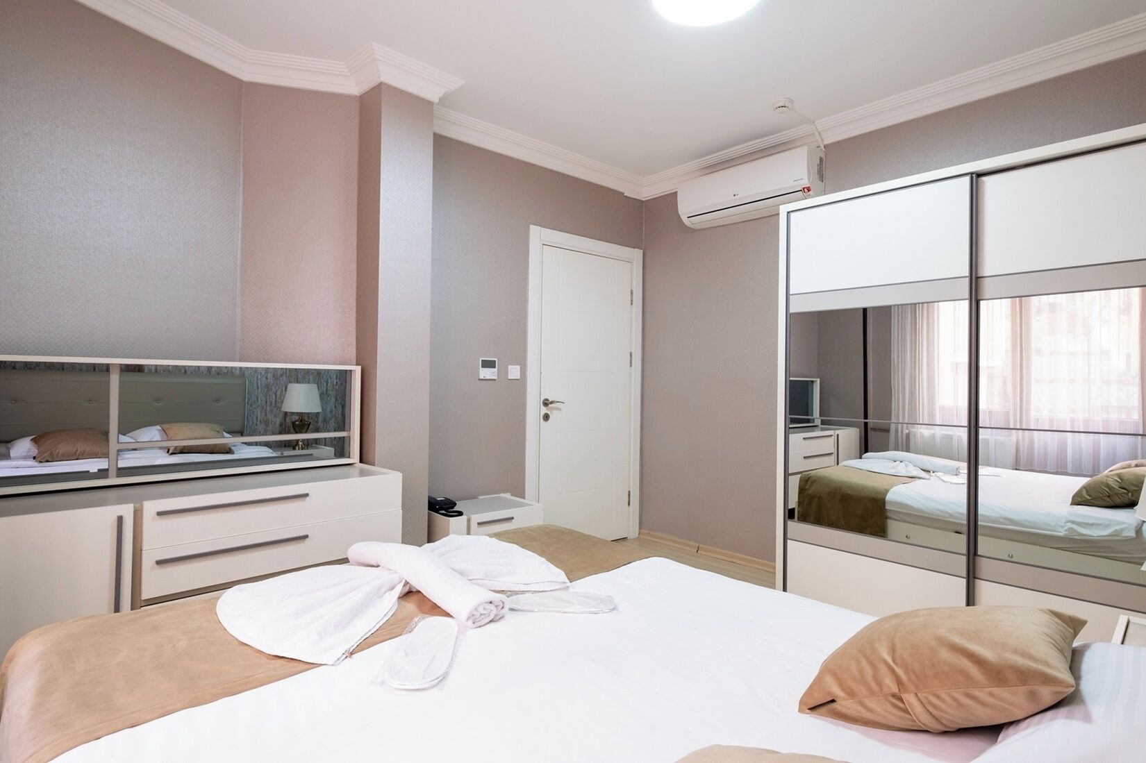 Une chambre d’hôtel équipée d’un lit, d’une table de chevet, d’un miroir, d’une armoire et d’un appareil de climatisation.