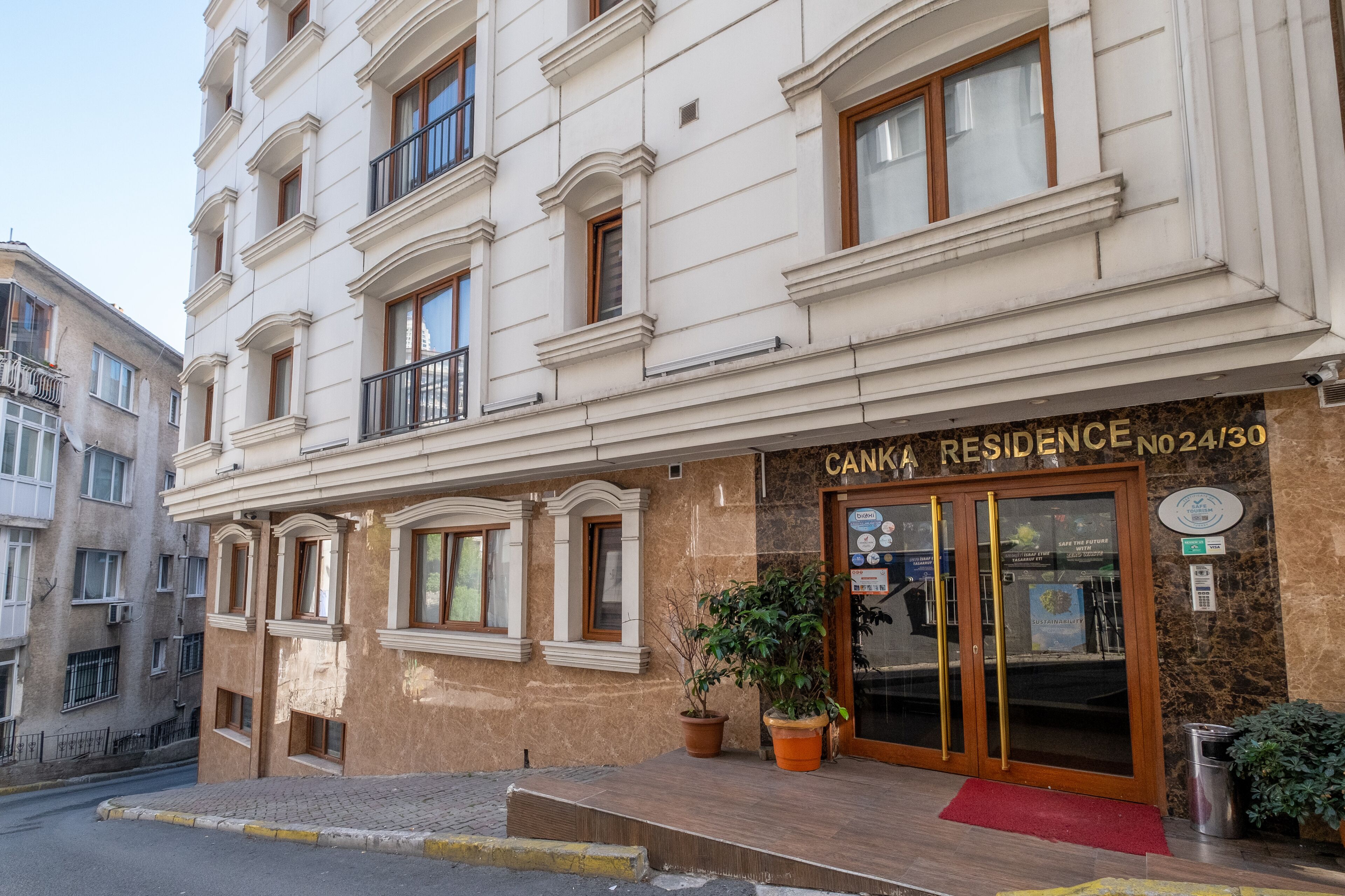 Un edificio de varios pisos con una entrada destacada que indica "CANKA RESIDENCE No 24/30".