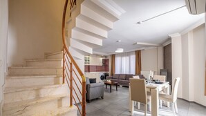 A spacious living area with a staircase, a dining table set for four, and a sofa. - The Canka Hotel Residance Istanbul (Istanbul)
