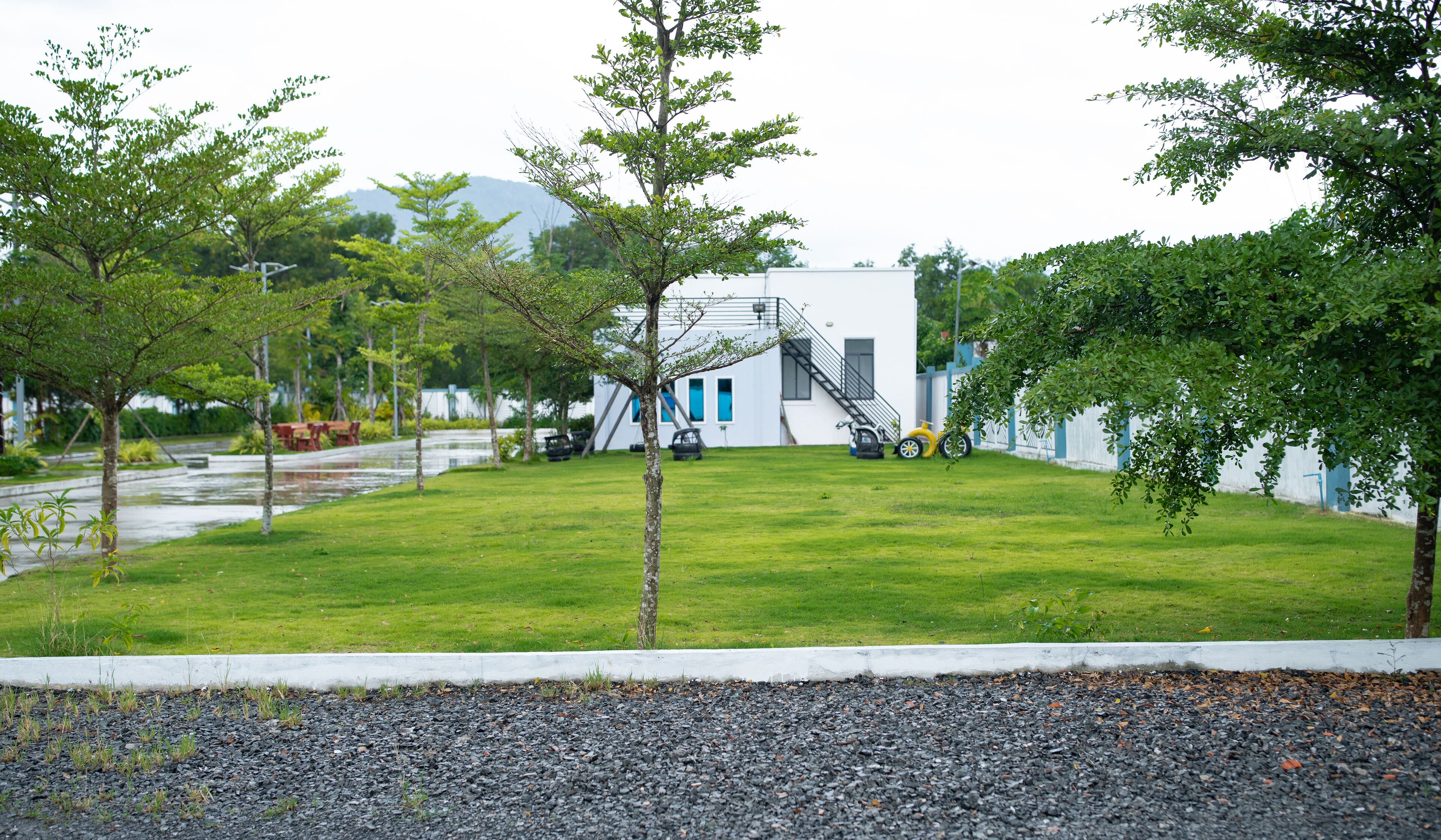 A modern building with a white exterior, a green lawn, and a gravel path in the foreground.