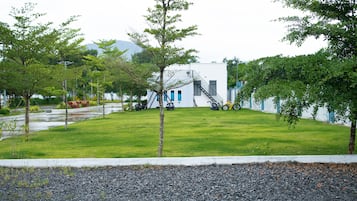 A modern building with a white exterior, a green lawn, and a gravel path in the foreground.