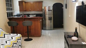 Una cocina moderna con armarios de madera, un refrigerador de acero inoxidable y una puerta negra que da a otra habitación.