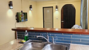 Una cocina con dos lavamanos de acero inoxidable, una encimera de madera y un salpicadero de azulejos.