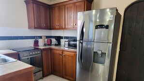 Una cocina con armarios de madera, un refrigerador de acero inoxidable, una estufa y un salpicadero de azulejos.