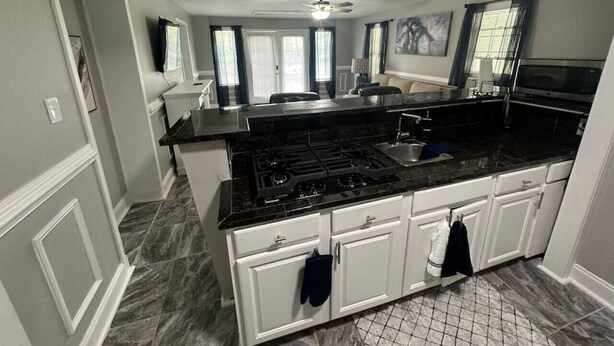 A kitchen with a central island, white cabinetry, and a black countertop. - Roomy & Newly Renovated Guest House, Kitchen, Desk, Pet Friendly, Shared Patio! (Ellenwood)