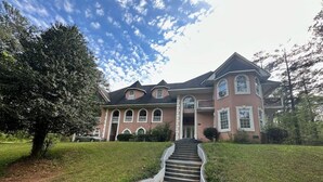 A large, two-story house with a prominent front entrance and a set of stairs leading up to it. - Roomy & Newly Renovated Guest House, Kitchen, Desk, Pet Friendly, Shared Patio! (Ellenwood)