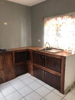 A kitchen with wooden cabinets, a sink, and a window with floral curtains.