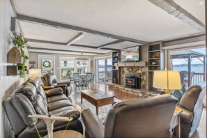 A spacious living area with leather sofas, a fireplace, and a view of the outdoors. - Sunset Point–Family Friendly, Lily Pad,& Swim Step (Lake Ozark)