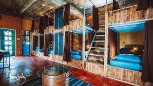 Una habitación rústica de madera con literas, una mesita de centro de cristal y una escalera.