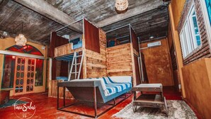 Una habitación con una cama litera, una escalera, una mesita y una lámpara colgante.