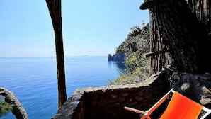 A stone wall with a wooden fence overlooking a calm sea. - Suite Baldea: An elegant and welcoming apartment that is part of an ancient watch tower built sheer above the sea, with Free WI-FI. (Positano)