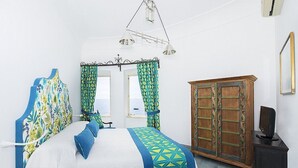 A bedroom with a bed, curtains, a wardrobe, and a desk. - Suite Baldea: An elegant and welcoming apartment that is part of an ancient watch tower built sheer above the sea, with Free WI-FI. (Positano)