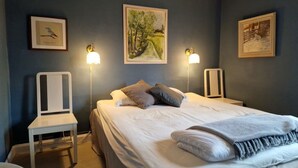 Una camera da letto con un letto, due comodini, una sedia e lampade a parete.