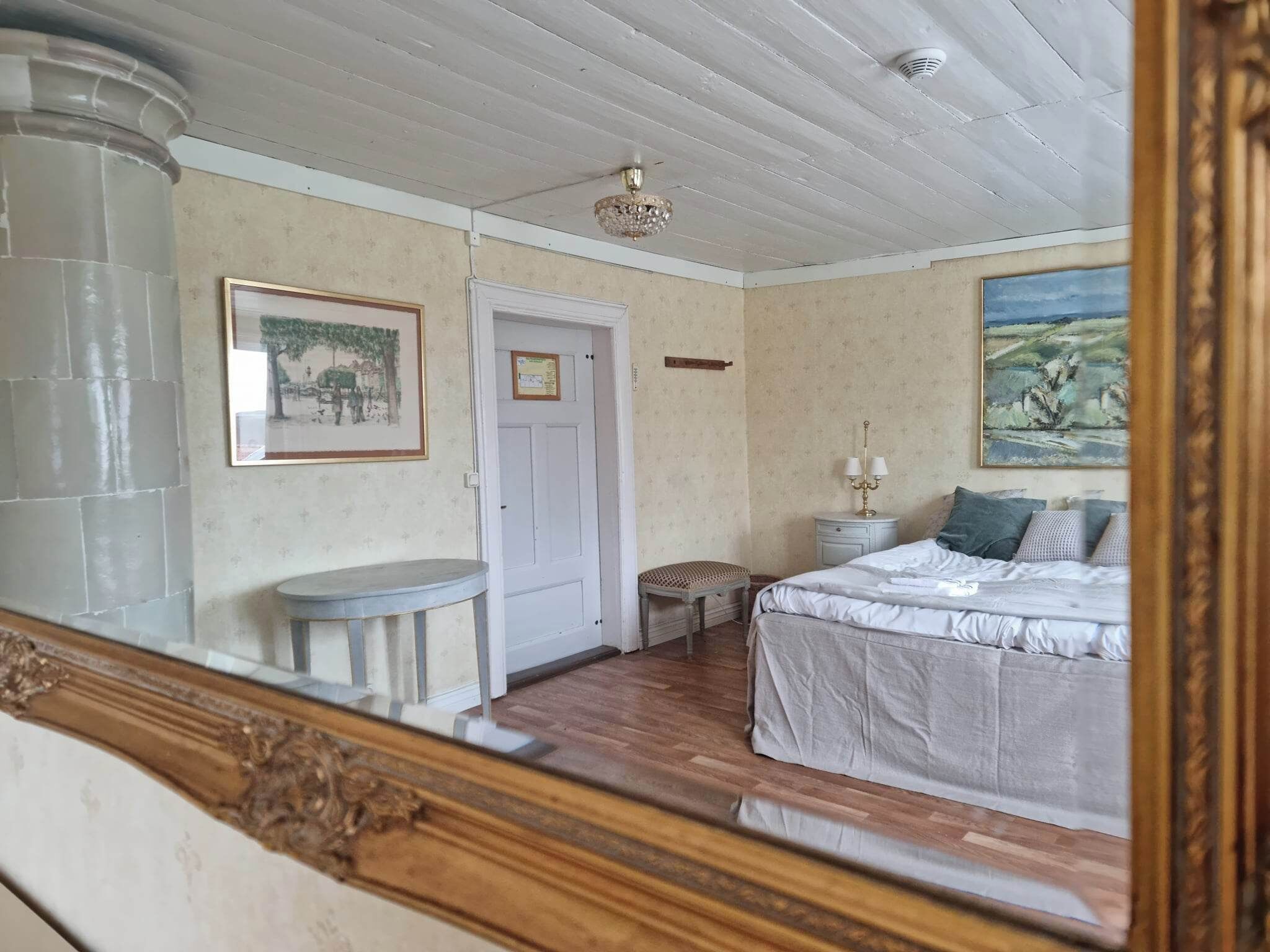 Une chambre à coucher avec un lit, une table de chevet, une chaise, une porte et un tableau au mur.