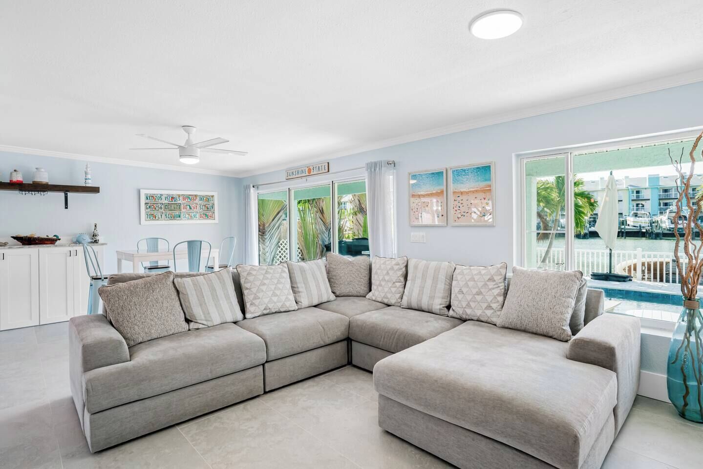 A modern living room with a sectional sofa, a dining area, and a view of the pool.