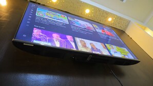 Ein flachbildfernseher an der Wand zeigt verschiedene Inhalte, darunter eine Kindersendung und ein Nachrichtensender.