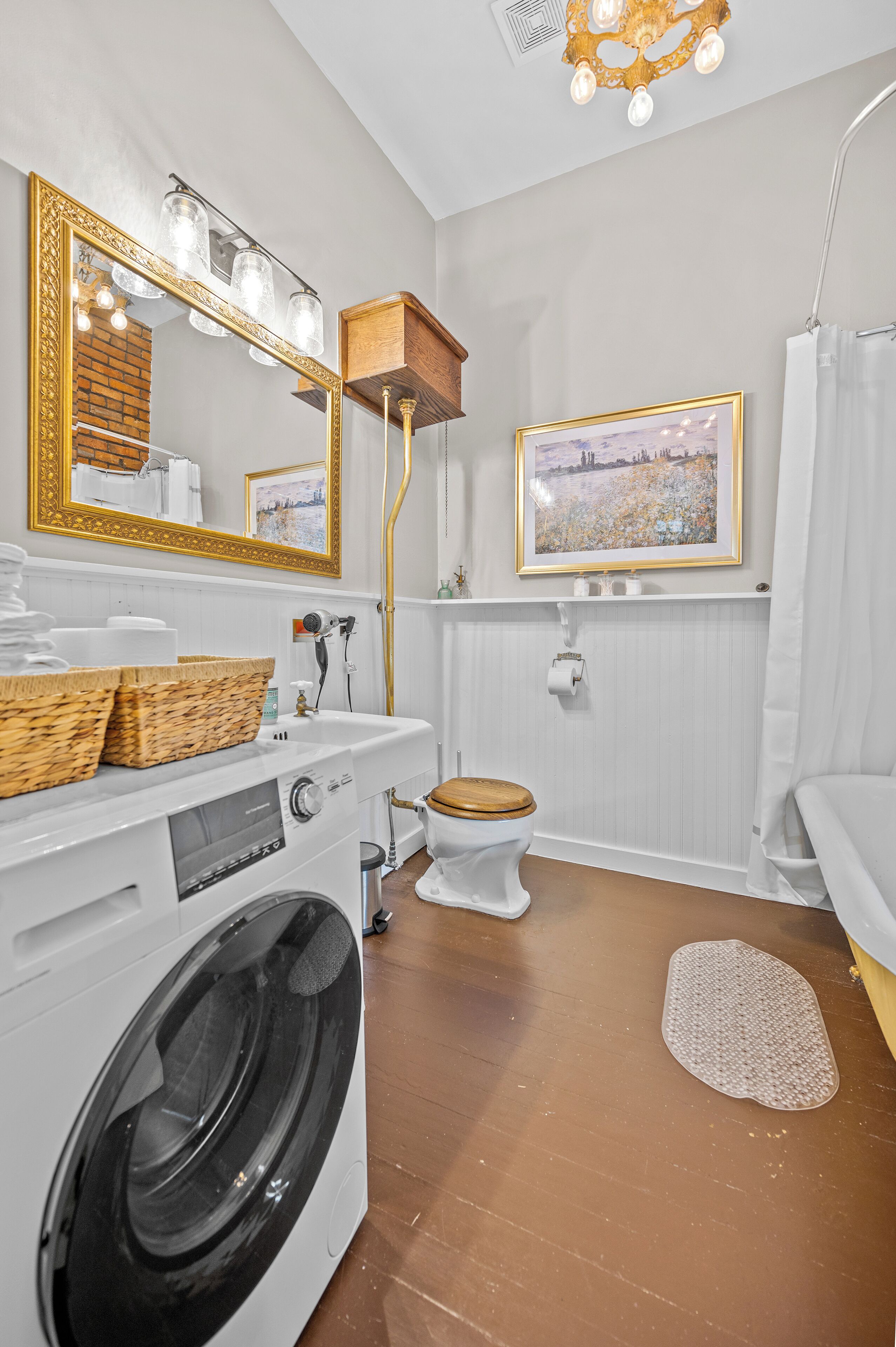 Une salle de bain moderne et compacte, équipée d’un lave-linge, de toilettes, d’un lavabo avec un miroir et d’un espace douche.