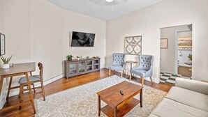 A spacious living room with a wooden dining table, two armchairs, a sofa, and a coffee table. - 30-Night Minimum South Main Apartment (Saint Charles)