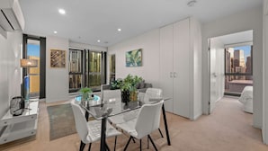 A modern apartment with a dining area, a large window, and a view of the city. - Lovely City Escape 2B2B Unit in Melbourne Central (Melbourne)