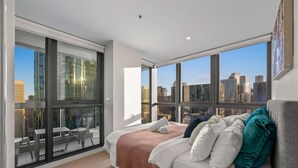 A modern bedroom with a large bed, a view of a cityscape through floor-to-ceiling windows, and a city view from the balcony. - Lovely City Escape 2B2B Unit in Melbourne Central (Melbourne)