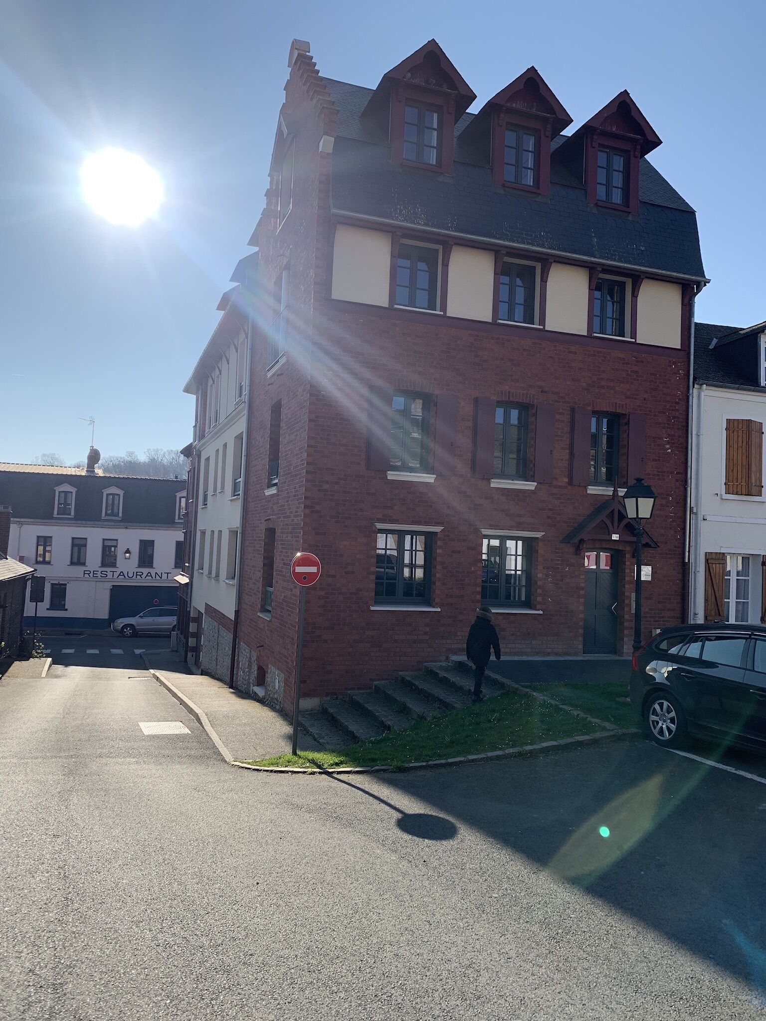 A multi-story building with a 'RESTAURANT' sign, a no entry sign, and a parked car.