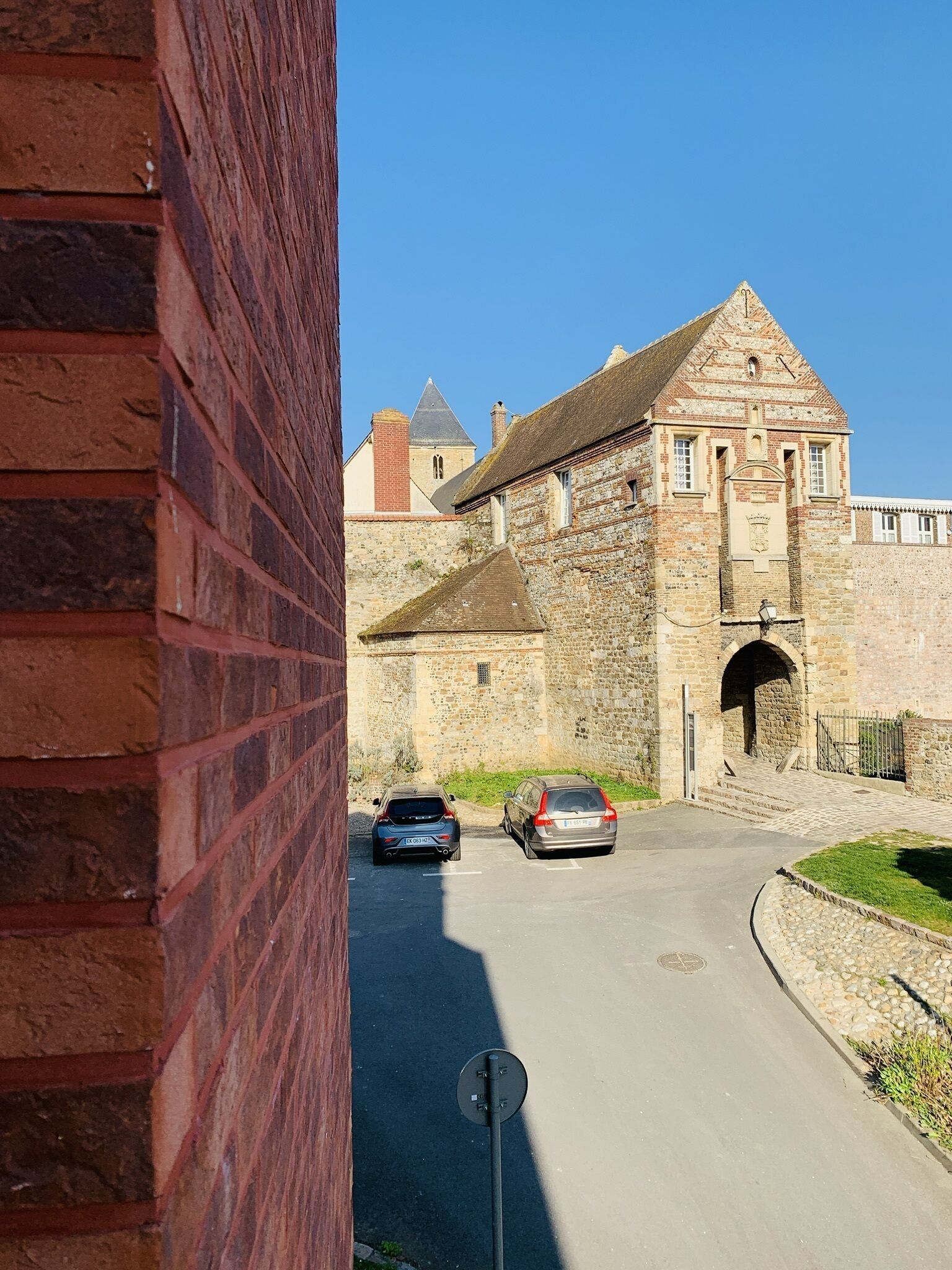 A historic stone building with a prominent archway and a small tower in the background.