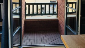 Un balcon doté d’un plancher en bois et offrant une vue sur les bâtiments voisins.