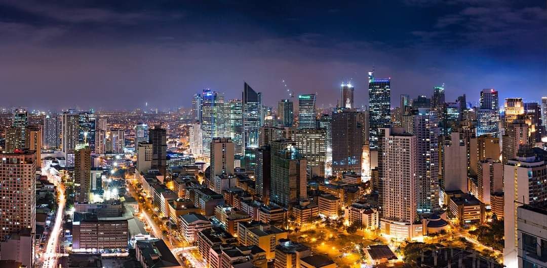 A nighttime cityscape with high-rise buildings and illuminated streets.