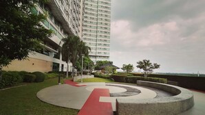 A modern building with a circular courtyard, a red pathway, and surrounding greenery. - Dimacs Staycation  (Makati)