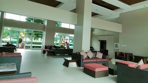 A spacious lobby with modern furniture, large windows, and a high ceiling. - Dimacs Staycation  (Makati)
